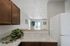 Bright and inviting kitchen with elegant marble countertops, warm wooden cabinets, and an open view into the spacious living area with large windows.