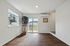 Bright living area with gleaming hardwood floors, large window, and sliding glass doors opening to a serene view.