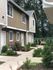 Charming townhouse with a cozy garden and inviting facade, set amidst lush greenery.
