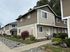 Charming townhouse with two stories featuring stylish siding, surrounded by lush landscaping and vibrant flowers, ideal for family living.