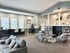 Bright communal living space with cozy seating, modern decor, and abundant natural light complemented by built-in bookshelves and a stylish work area.