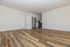 Modern apartment interior showcasing sleek wooden floors and a compact kitchen with elegant cabinetry and stainless steel appliances.