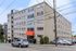 Charming multi-story apartment building with modern design and vibrant red awning, surrounded by convenient parking and lush greenery.