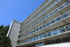Modern apartment building with glass balconies and sleek architectural design, set against a clear blue sky.