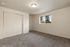 Bright and inviting bedroom featuring soft carpet, a large window with scenic views, and ample closet space with sliding doors.