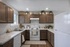 Charming kitchen with rich wooden cabinets, sleek white appliances, and elegant marble countertops adorned with plants and decor.