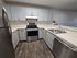 Modern kitchen with sleek stainless steel appliances, elegant white cabinetry, and stylish dark wood flooring.