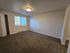 Spacious, bright apartment bedroom featuring plush carpeting, a large window, and a built-in closet.