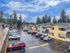 Inviting apartment complex with modern architecture, spacious parking, and lush green surroundings under a vibrant blue sky.