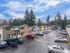 Charming suburban apartment complex with colorful townhouses and ample parking, surrounded by lush greenery and a clear blue sky.