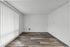 Bright and spacious room with elegant wood flooring and large vertical blinds, ideal for creating a personalized living space.