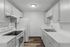 Elegant kitchen with sleek white cabinetry, modern appliances, and stylish wood flooring emphasizing simplicity and function.