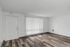 Contemporary living space with sleek hardwood floors and ample natural light through large window blinds.