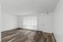 Bright and welcoming living space with elegant hardwood flooring and large vertical blinds, offering a blank canvas for personalized design.