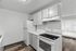Contemporary kitchen with sleek white cabinets, modern appliances, and elegant wood flooring, flooded with natural light.