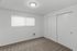 Bright and inviting room featuring sleek white walls, plush carpet, and ample natural light through a large window.