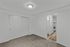 Inviting bedroom with plush carpet and a sleek sliding closet door, leading into a stylish kitchen area with modern appliances.