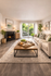 Inviting living room with a cozy fireplace, elegant decor, and a lush garden view through sliding glass doors.
