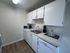 Modern kitchen with sleek white cabinets, stainless steel sink, and inviting decor, offering functionality and style in a cozy space.