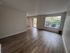 Bright, spacious living area with modern wood flooring and large windows overlooking green scenery.