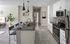 Spacious kitchen with white shaker cabinets, dark quartz counters, and pantries at Campus Circle in Gainesville, Florida