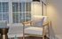 A cozy Centennial Ridge living room corner featuring a modern armchair, soft lighting, and large windows with blinds.