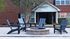 Centennial Village outdoor patio common area with four stylish wooden chairs surrounding a circular stone fire pit.