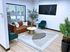 Centennial Village leasing office lounge with a stylish brown leather sofa, green armchair, and modern decor.
