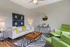 Inviting living room with modern decor, featuring a white sofa accented with yellow pillows, green armchairs, and a stylish wooden coffee table on a geometric rug.