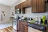 Modern kitchen with sleek dark wood cabinets, stainless steel appliances, and stylish subway tile backsplash.