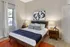 Inviting bedroom featuring a chic wooden bed, stylish abstract art, and warm ambient lighting.