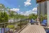 Charming apartment balcony with vibrant blue chairs offering scenic views of lush greenery and a tranquil river under a clear blue sky.