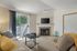 Canyon Springs apartment living room with cozy fireplace stylish decor and glass doors to leafy outdoor view in Lynnwood WA