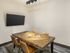 Cozy and modern meeting room in Republic on Main apartment featuring a stylish wooden table, leather chairs, and a mounted flat-screen TV, ideal for collaboration.