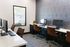 Modern workspace with sleek brown chairs, stylish wallpaper, and abundant natural light from large window.