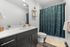 Modern bathroom featuring a sleek vanity, stylish green shower curtain, and chic open shelving, offering elegance and functionality.
