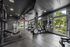 Contemporary fitness center with state-of-the-art exercise equipment, large windows showcasing lush greenery, and a vibrant sports-themed mural.