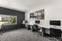 Modern shared workspace with sleek desks, computers, and a large window offering natural light and a view, ideal for productivity.