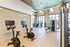 Indoor gym with stationary bikes, treadmills, and stair climbers equipped with touch screen displays.