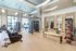 An indoor gym with high ceilings, tall windows, wood-style floors, and 4 mirrored doors along the wall. Equipment includes stationary bikes, weight machines, medicine balls, treadmills, and ellipticals.