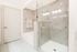 Bathroom with a frameless glass walk-in shower, large soaking tub, and white marble tile on the floors and the walls of the shower and bath.