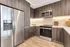 Kitchen with handleless dark wood cabinets, light wood-style floors, stainless steel appliances, and white quartz countertops.