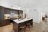Kitchen with stainless-steel appliances, modern dark wood cabinetry, a white marble island with three bar stools and light wood-style floors.