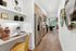 View from down the hall of a studio apartment kitchen with stainless-steel appliances. A built-in desk with shelves is in the foreground.