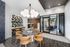Four mid-century modern curved wood chairs around a gray marble table with a view into the glass-walled conference room. A desk area is set into the wall with a mosaic backsplash.