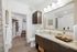 Spacious bathroom with dark wood cabinetry, large vanity with a granite countertop, and a walk-in closet.