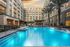 Resort-style pool with palm trees, landscaping, a covered dining/grilling area, a raised fountain, and terraced seating.