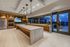 A clubhouse kitchen facing full window walls with a city skyline view. The floors, walls, and columns are marble-clad.