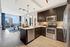 Kitchen with warm wood-style floors, dark wood cabinets, stainless appliances, granite countertops, and a recessed ceiling