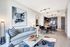 Spacious living and dining areas with warm wood-style floors, floor-to-ceiling windows, a large sofa, and a 4-person round dining table